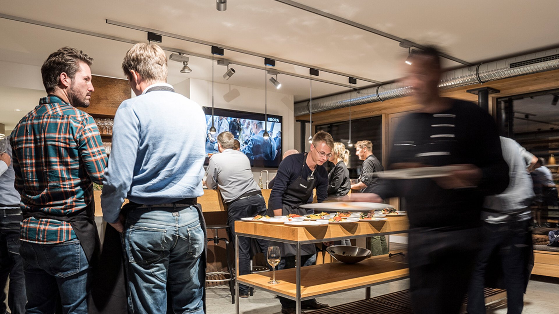 Besucher im modernen BORA Showroom bei Produktpräsentation und Gespräch vor innovativer Küchenausstellung.
