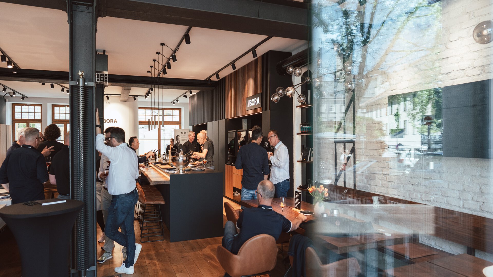 BORA Showroom mit Besuchern, modernen Küchen und Dunstabzugssystemen in ansprechendem Ambiente.