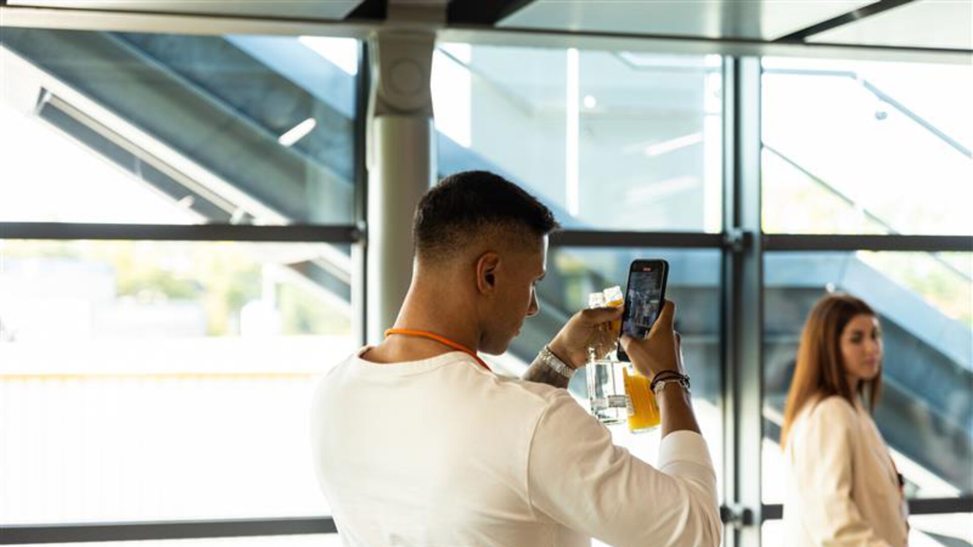 Mann fotografiert Produkt mit Smartphone bei BORA Event in modernem, lichtdurchflutetem Raum.