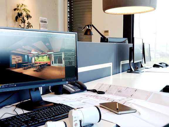 Arbeitsplatz mit BORA Designentwurf am Bildschirm, Büromaterial und moderner Bürobeleuchtung.