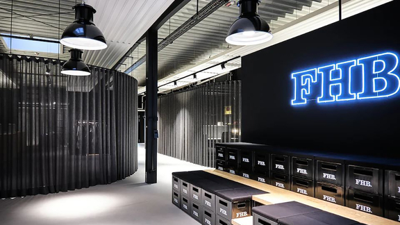 Moderner Showroom mit BORA Design und FHB-Markenbranding, minimalistische Sitzbänke und industrielle Beleuchtung.
