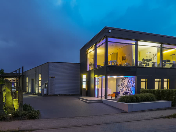 BORA Firmengebäude bei Abendlicht mit moderner Architektur und beleuchteten Innenräumen.