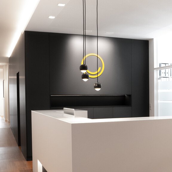Moderner Empfangsbereich der Marke BORA mit schwarzer Wand, gelbem Logo und minimalistischer weißer Theke.