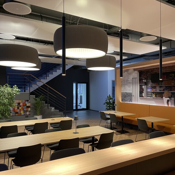 Moderne BORA Lounge mit stilvoller Beleuchtung, Sitzbereichen und offener Raumgestaltung für kreative Meetings und Pausen.