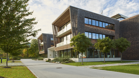 Moderner BORA Firmenhauptsitz mit Holzfassade und großen Fenstern in naturnaher Umgebung bei Tageslicht.