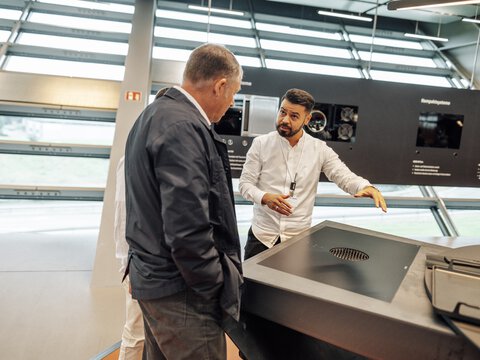 Zwei Männer betrachten und erläutern ein BORA Kochfeld mit integriertem Dunstabzug in moderner Ausstellung.