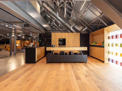Moderne BORA Kücheninsel mit integriertem Kochfeld und minimalistischer Holz- und Metalldesign-Kombination in showroomähnlicher Umgebung.