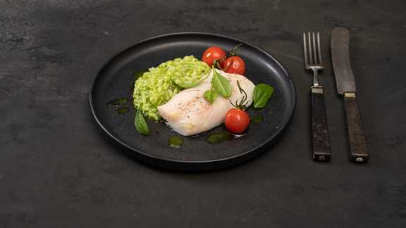 Leckeres Gericht mit Fisch, Tomaten und grünem Risotto auf schwarzem Teller, inszeniert für BORA Küchenkomfort.