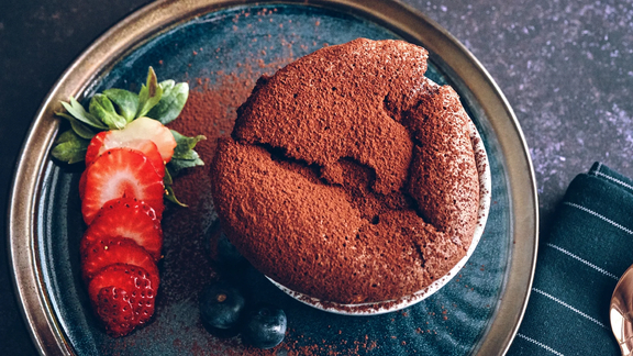 Schokoladen-Soufflé auf blauem Teller mit frischen Erdbeeren, präsentiert auf einer BORA Küchenarbeitsfläche.