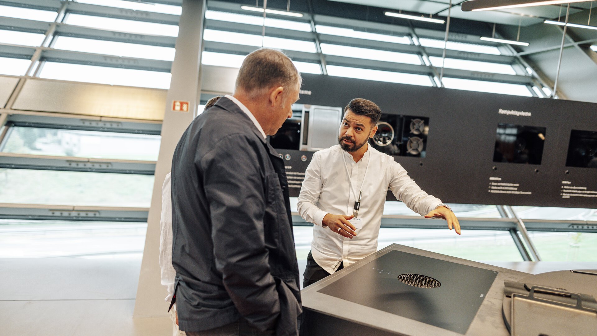 Zwei Personen besprechen BORA Kochfeld mit integriertem Abluftsystem in modernem Showroom.