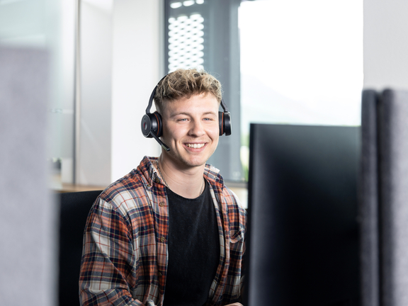 Mann mit Kopfhörern arbeitet an Computer, keine BORA-Produkte sichtbar.