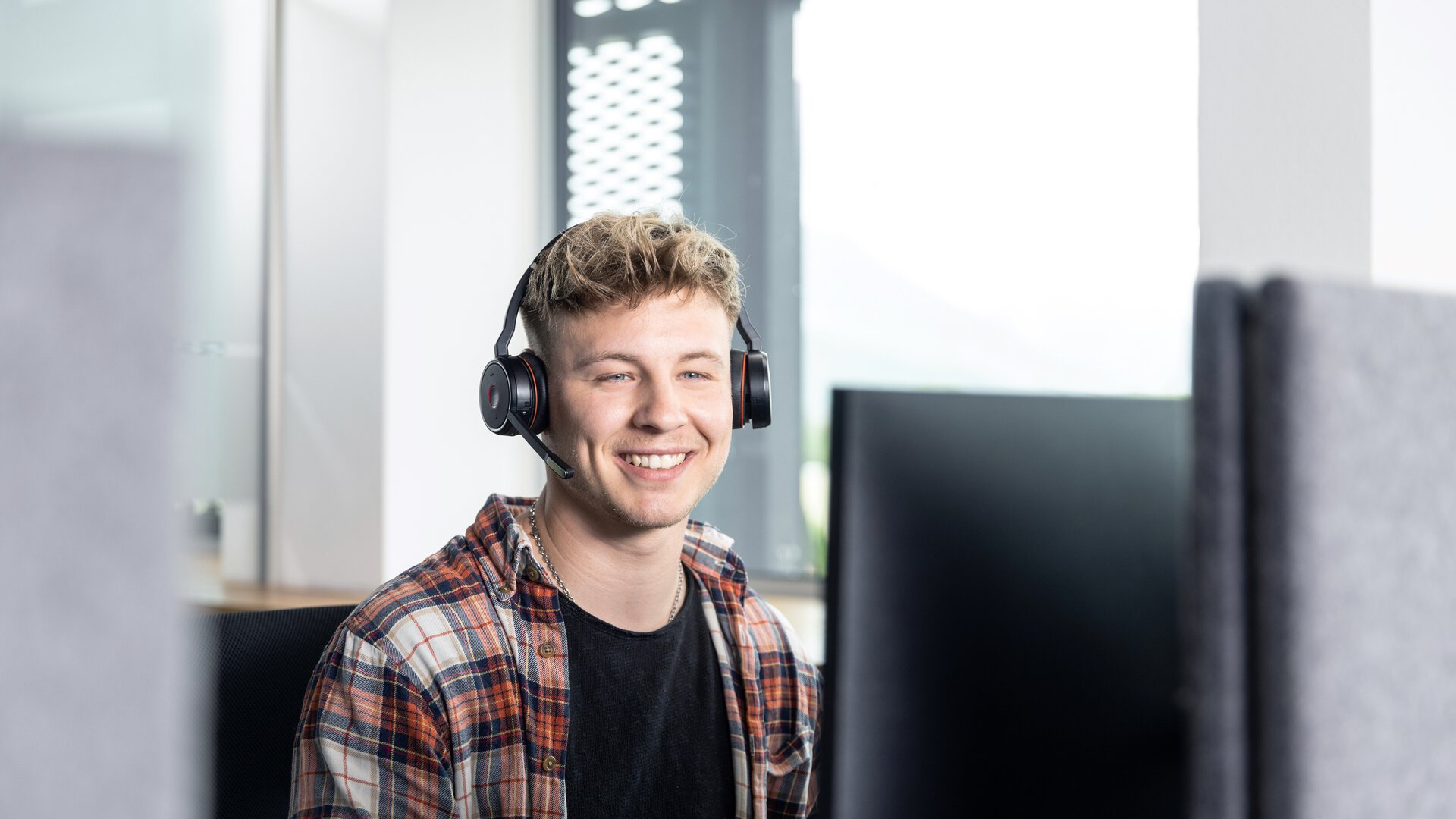 Mann mit Kopfhörern arbeitet an Computer, keine BORA-Produkte sichtbar.