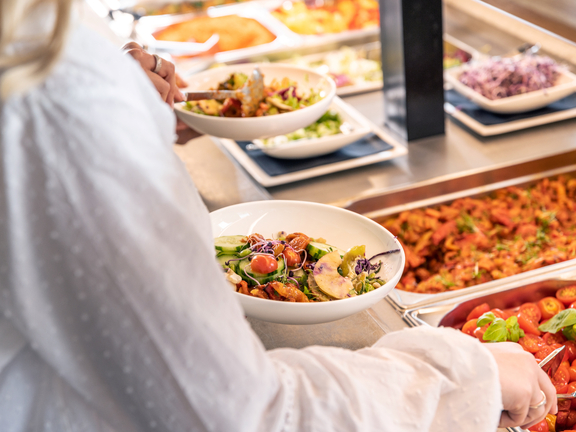Person nimmt frischen Salat an BORA Buffet mit verschiedenen Beilagen und hochwertiger Präsentation.