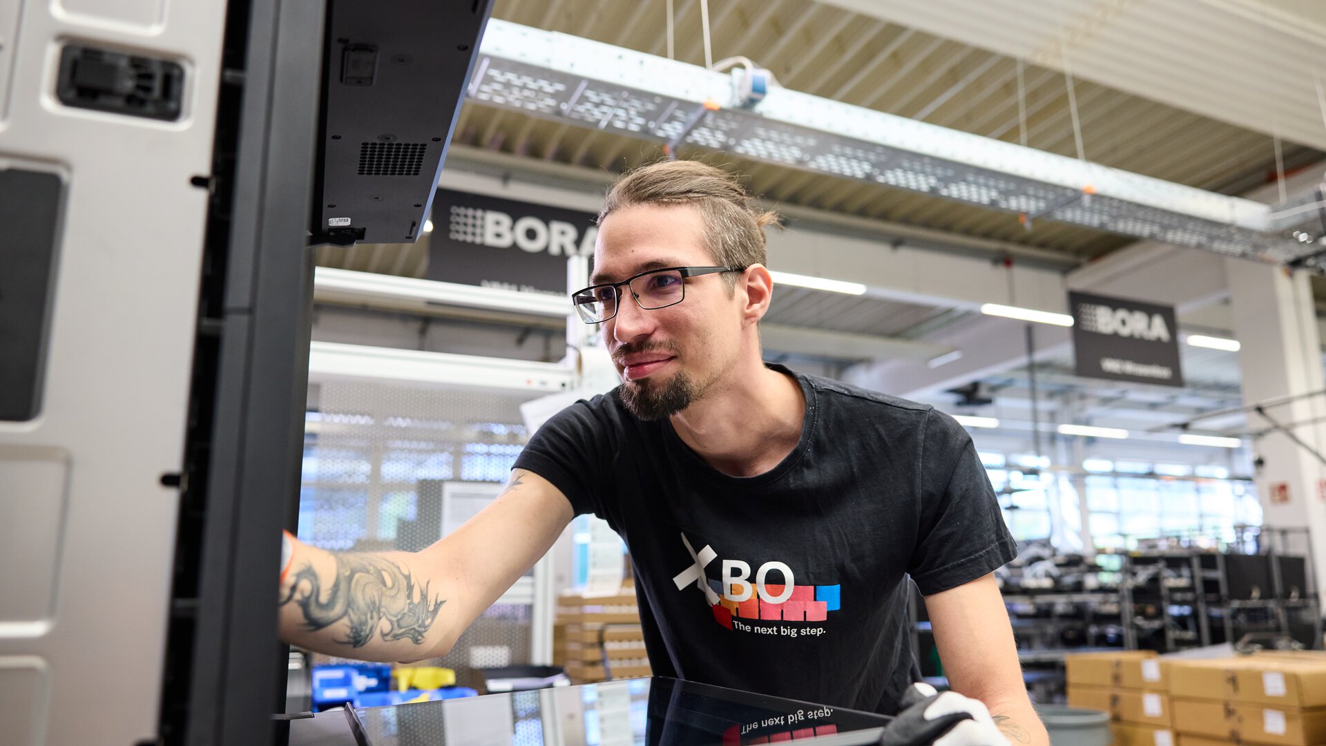 Mitarbeiter montiert BORA Kochfeldabzug in moderner Produktionsumgebung mit BORA Branding.