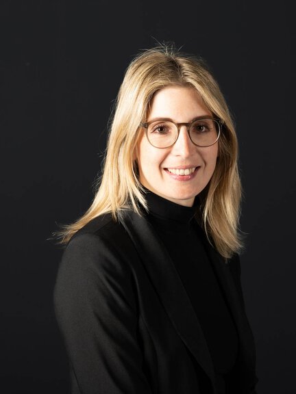 Frau in schwarzem Outfit vor dunklem Hintergrund, kein BORA-Produkt sichtbar.