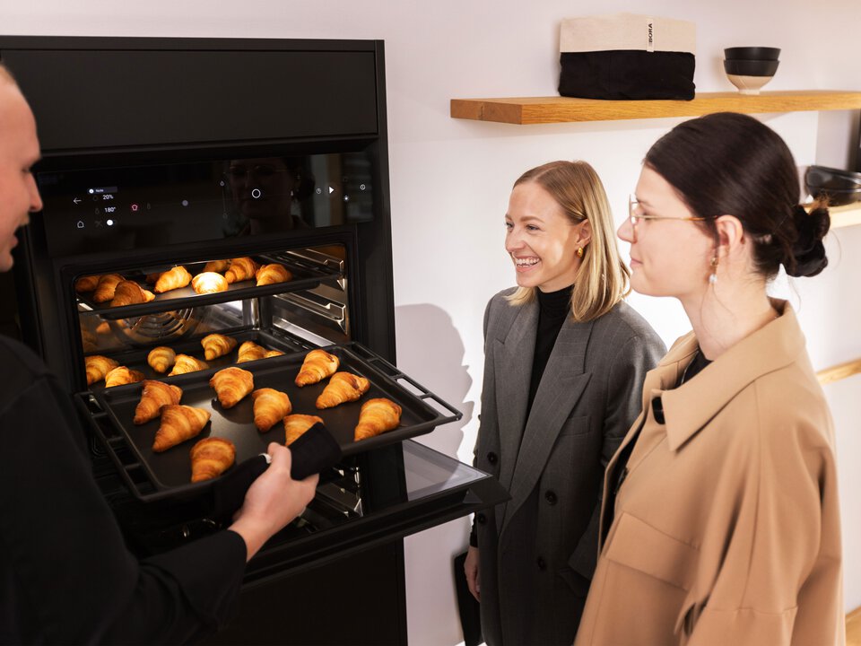 BORA Backofen mit frischen Croissants, gezeigt während einer Produktvorführung vor zwei Kundinnen.
