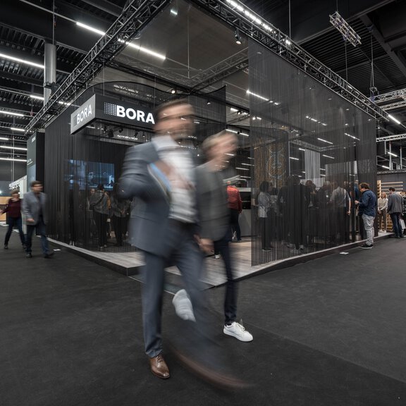 Messestand der Marke BORA auf einer Fachmesse mit zahlreichen Besuchern und moderner Präsentation.