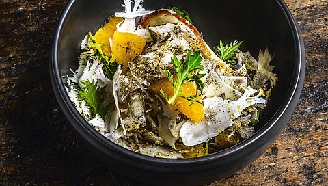 Ensalada de coliflor y naranja espolvoreada con té negro y servida con trocitos de pan crujientes