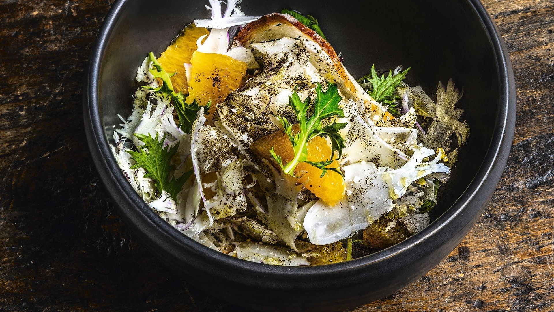 Ensalada de coliflor y naranja espolvoreada con té negro y servida con trocitos de pan crujientes