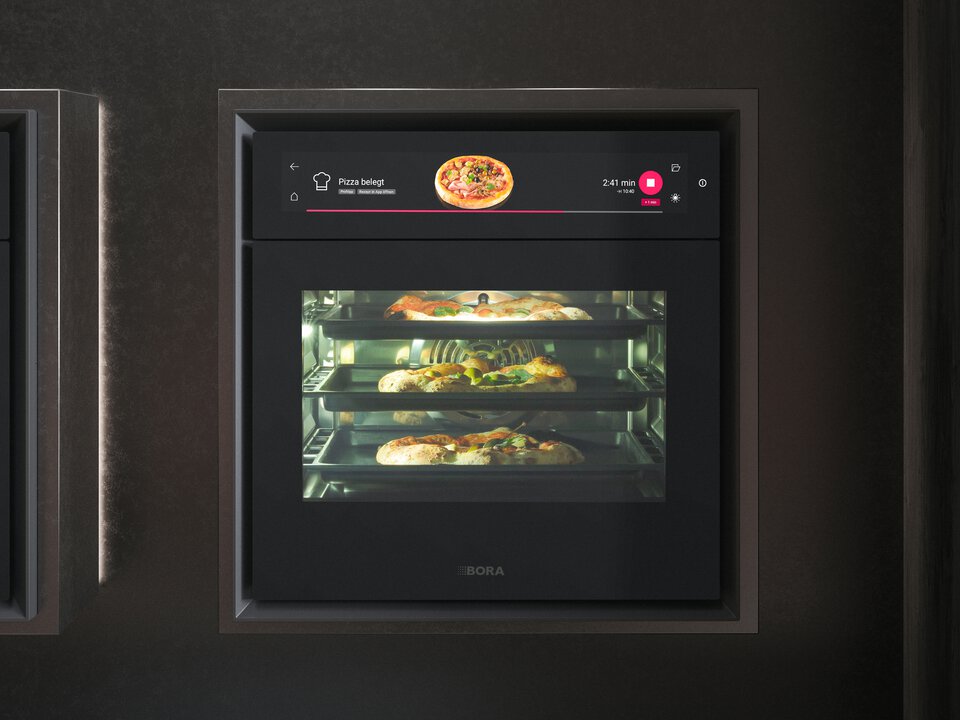 BORA Einbaubackofen mit digitalem Display, drei Ebenen und verschiedenen Pizzen im Inneren, modernes Küchendesign.