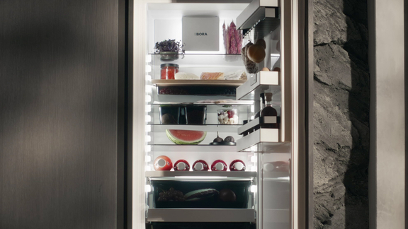 Offener BORA Kühlschrank mit organisiertem Innenraum und vielfältigen Lebensmitteln, eingebaut in moderne Küchenfront. Offener BORA Kühlschrank mit organisiertem Innenraum und vielfältigen Lebensmitteln, eingebaut in moderne Küchenfront.