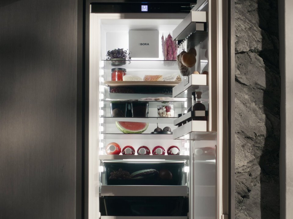 Offener BORA Kühlschrank mit organisiertem Innenraum und vielfältigen Lebensmitteln, eingebaut in moderne Küchenfront.