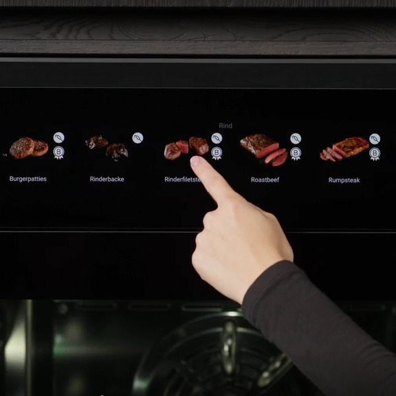 Hand bedient BORA Kochfeld-Display mit Auswahl verschiedener Rindfleischgerichte wie Burgerpatties und Rumpsteak.