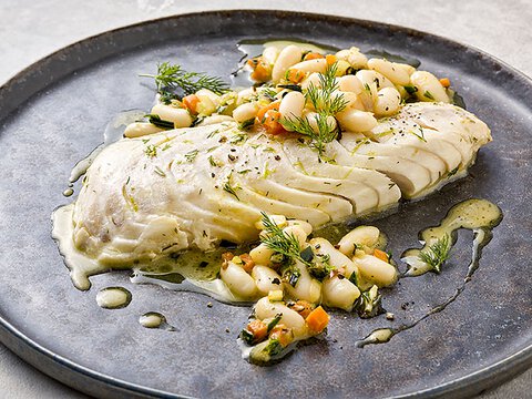 BORA Gericht mit gegartem Fischfilet und weißen Bohnen, zubereitet auf BORA Kochfeld mit Dampfgarfunktion.