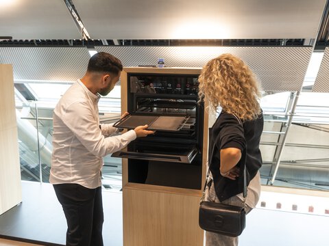 Zwei Personen betrachten einen BORA Einbau-Backofen in moderner Ausstellung.