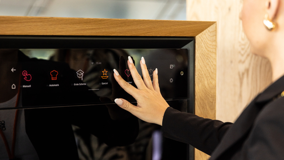 Frau bedient BORA Backofen mit Touch-Display in moderner Küchenumgebung. Frau bedient BORA Backofen mit Touch-Display in moderner Küchenumgebung.
