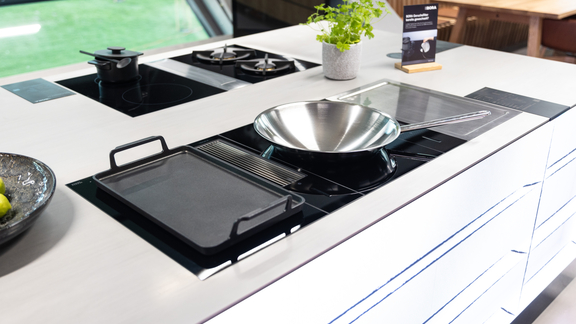 BORA Kochfeld mit integriertem Lüftungssystem, Pfanne und Grillplatte auf moderner Kücheninsel. BORA Kochfeld mit integriertem Lüftungssystem, Pfanne und Grillplatte auf moderner Kücheninsel.