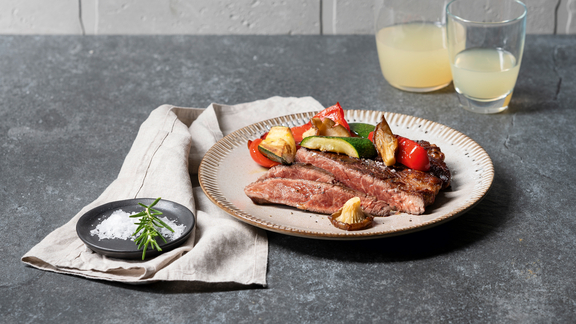 BORA Servierplatte mit gegrilltem Steak und Gemüse, Beilage mit Rosmarin und Salz auf dunklem Tisch. BORA Servierplatte mit gegrilltem Steak und Gemüse, Beilage mit Rosmarin und Salz auf dunklem Tisch.