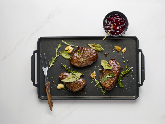 BORA Grillplatte mit perfekt gebratenem Steak, Kräutern und Dip auf weißem Untergrund.
