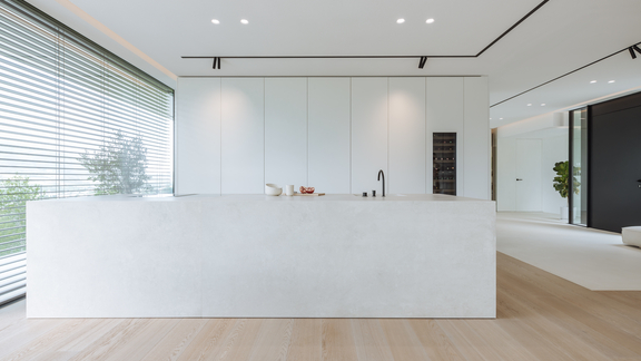 Moderne weiße BORA Küche mit minimalistischer Insel, integrierter Dunstabzug und hellem Parkettboden.