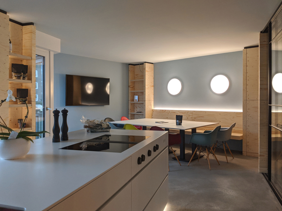 Moderne Küche mit BORA Kochfeld und integriertem Dunstabzug, kombiniert mit Essbereich und stilvoller Holz- und Lichtgestaltung.