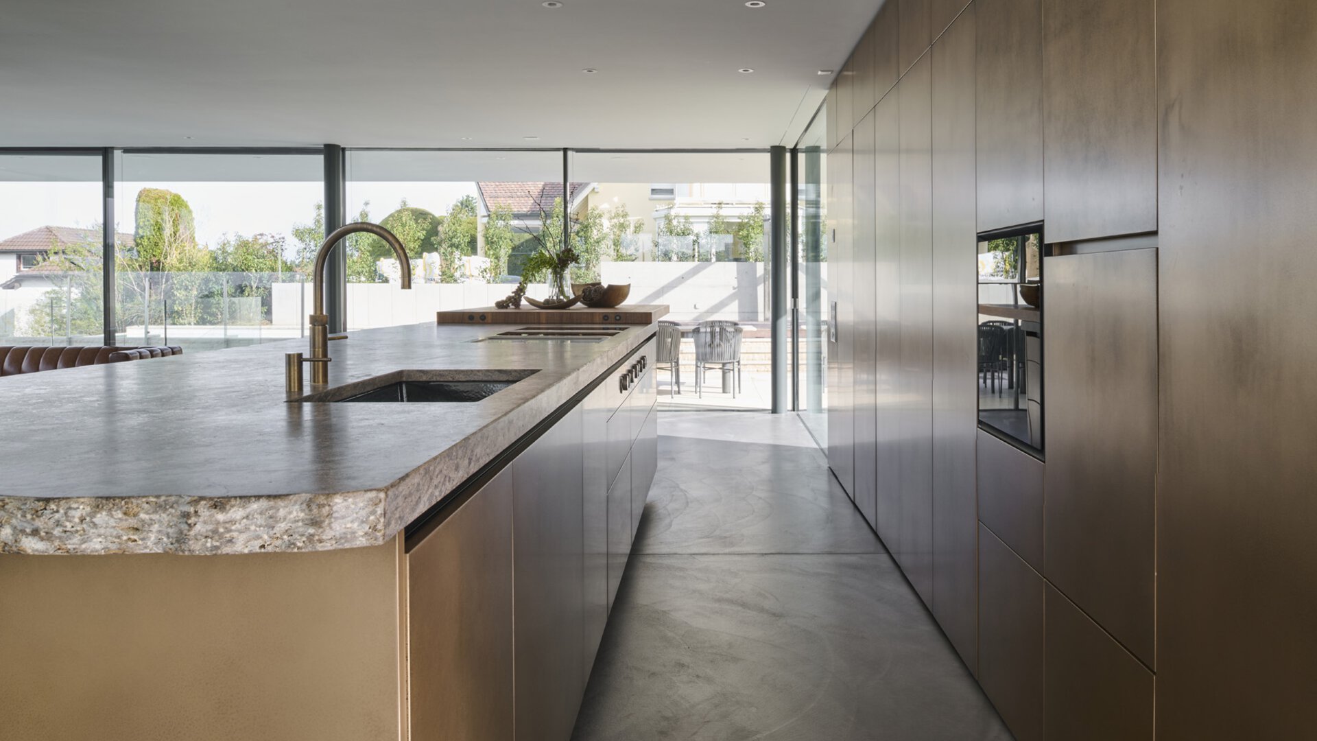 Moderne BORA Küche mit Kücheninsel, integriertem Spülbecken und minimalistischer Holzfront in offenem Raum.