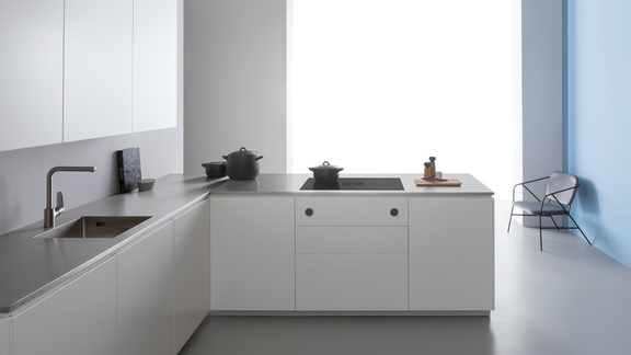Moderne BORA Kücheninsel mit integriertem Kochfeld und Dunstabzug sowie minimalistischer weißer Küchenfront und grauer Arbeitsplatte. Moderne BORA Kücheninsel mit integriertem Kochfeld und Dunstabzug sowie minimalistischer weißer Küchenfront und grauer Arbeitsplatte.