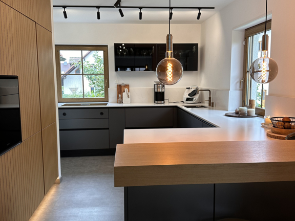 Moderne Küche mit BORA Kochfeldabzug, schwarzer Einbauküche und Holzarbeitsplatte, offene Raumgestaltung und Fensterlicht. Moderne Küche mit BORA Kochfeldabzug, schwarzer Einbauküche und Holzarbeitsplatte, offene Raumgestaltung und Fensterlicht.