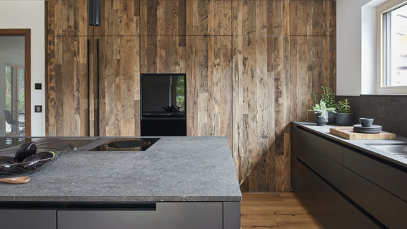 Moderne BORA Kücheninsel mit integriertem Kochfeld und Dunstabzug, dunkle Fronten und Holzpaneele in hochwertiger Designküche.