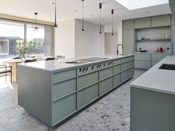 Moderne Küche mit BORA Kochfeld und integriertem Kochfeldabzug, grüne Fronten und großzügige Kücheninsel im Tageslicht. Moderne Küche mit BORA Kochfeld und integriertem Kochfeldabzug, grüne Fronten und großzügige Kücheninsel im Tageslicht.