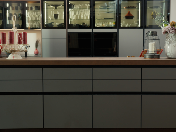 Moderne BORA Kücheninsel mit Holzarbeitsplatte und grauen Schubladen, umgeben von eleganten Küchenschränken und Deko-Elementen. Moderne BORA Kücheninsel mit Holzarbeitsplatte und grauen Schubladen, umgeben von eleganten Küchenschränken und Deko-Elementen.